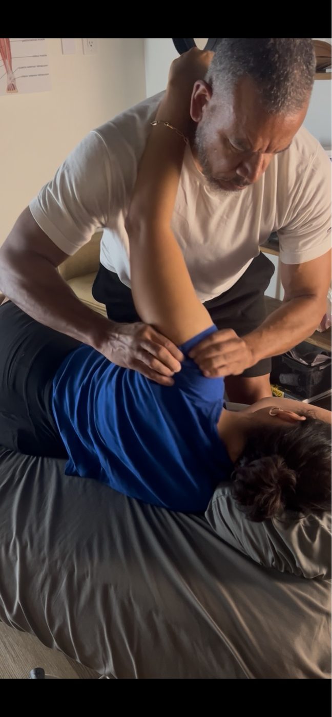 Brian Greaves performing neuromuscular therapy on a client — precise, hands-on shoulder work