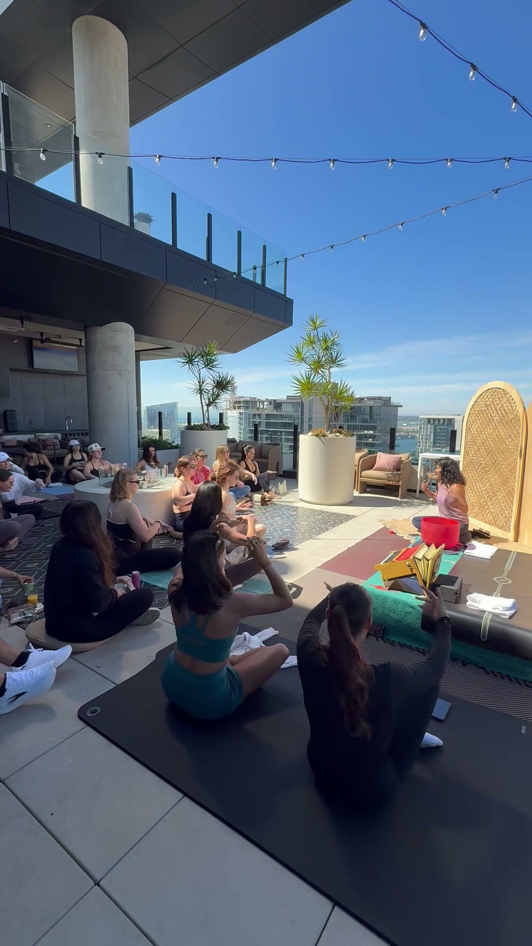Dr. Deepthi Sudhakar leading a rooftop meditation class with singing bowl at sunset