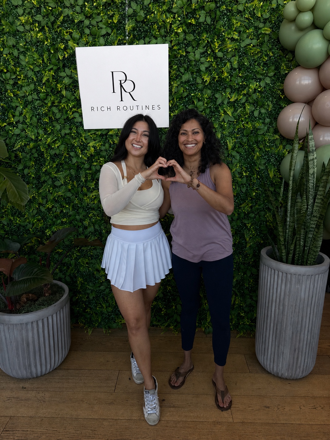 Eva and Dr. Deepthi Sudhakar making a heart with their hands at a wellness event