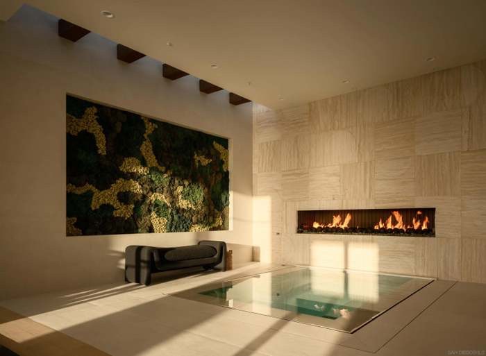 Cold plunge and preserved moss wall beside a linear travertine fireplace