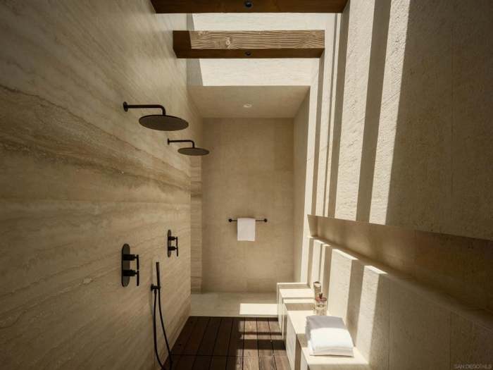 Dual-head rain shower in travertine, lit by skylight