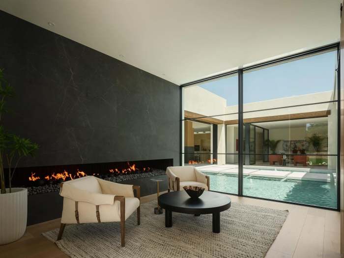 Indoor sitting room with linear fireplace and floor-to-ceiling pool view